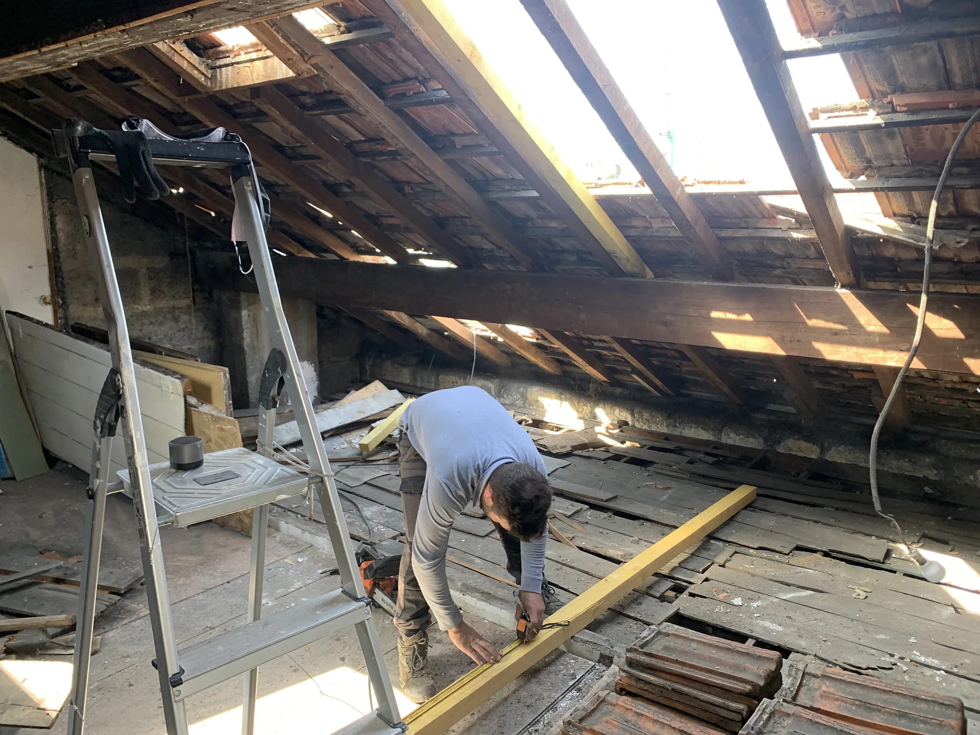 Artisan intervenant sur une pièce de bois à l’intérieur d’une charpente découverte