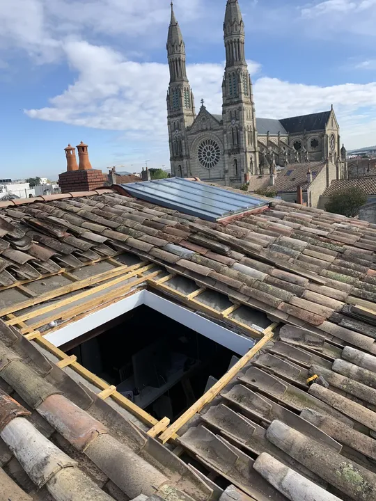 Ouverture préparée dans une toiture en tuiles avec chevrons visibles