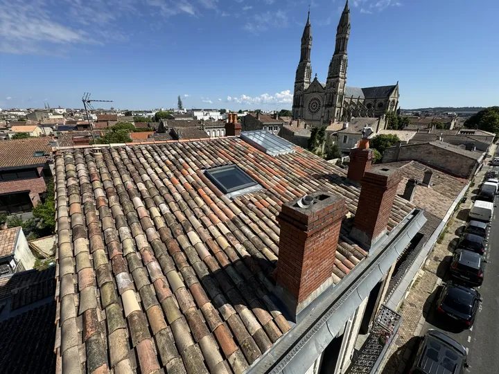 Toiture en tuiles avec une verrière et des flèches d’église à l’arrière-plan