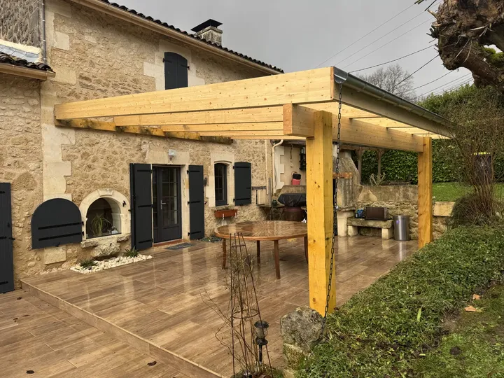 Structure extérieure en bois avec poteaux et poutres devant une maison