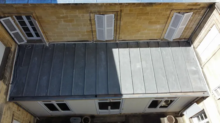 Vue plongeante sur une couverture métallique à joints debout contre une façade