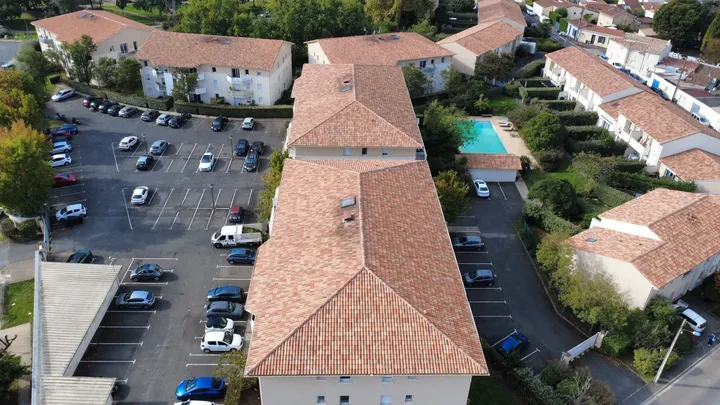 Vue aérienne de longues toitures en tuiles au sein d’une résidence